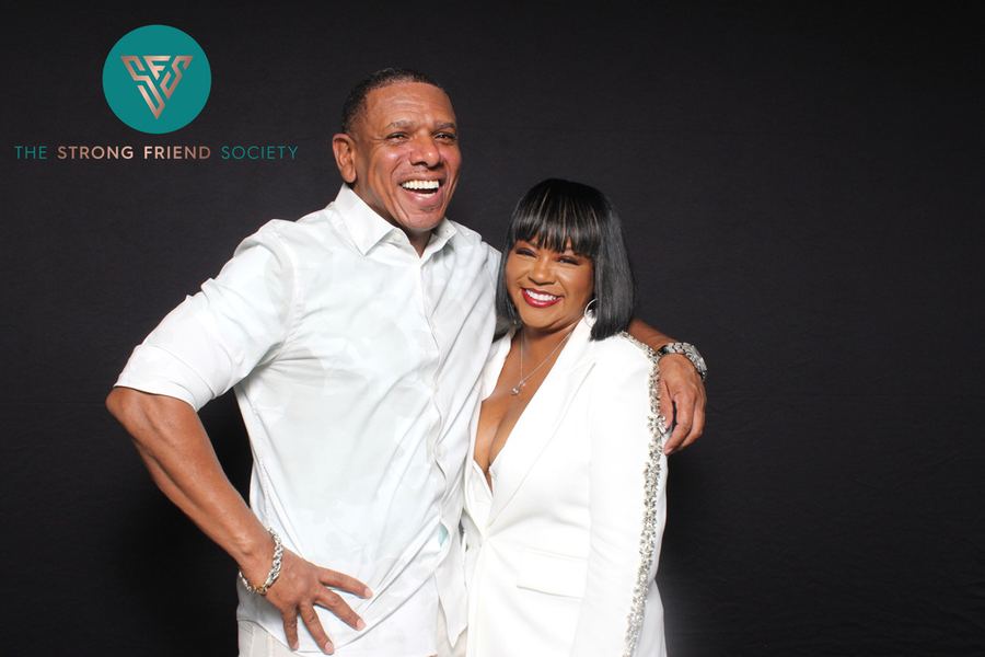 Two guests photographed at a private members&rsquo; event, with the host organisation&rsquo;s logo on the image.